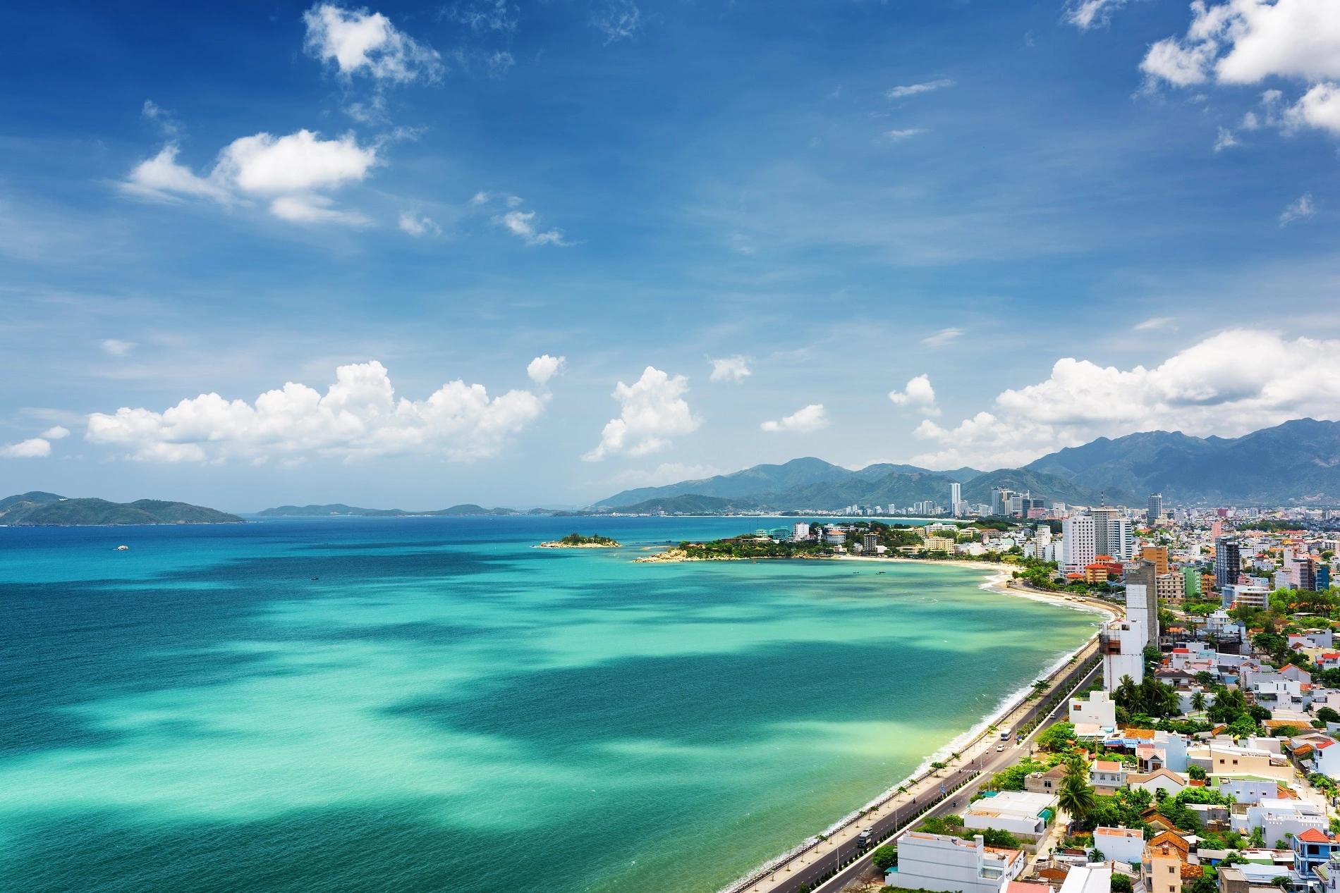 Vịnh biển rộng với mặt nước xanh và dải đô thị ven bờ nhìn từ trên cao
